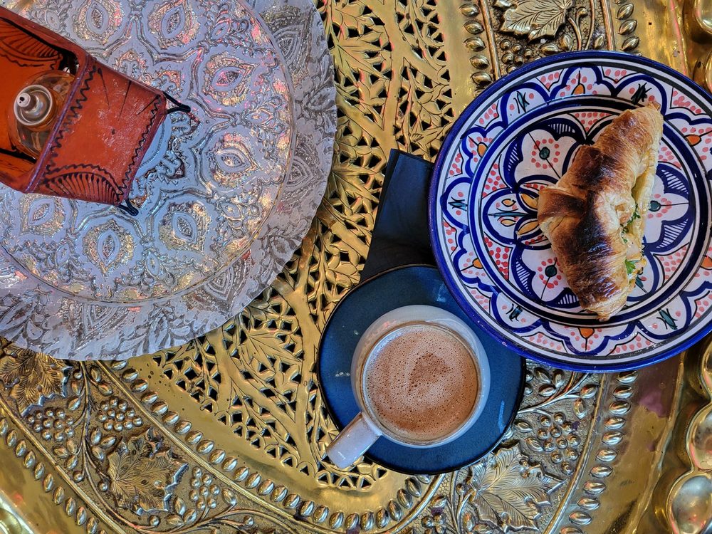 Overhead view of coffee and pastry on ornate brass tray